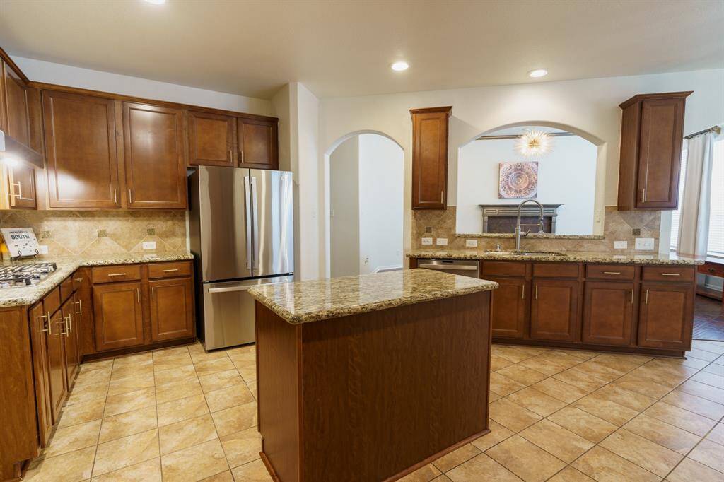 Modern kitchen with a sleek five burner gas cooktop on granite countertops and a stylish tiled backsplash.