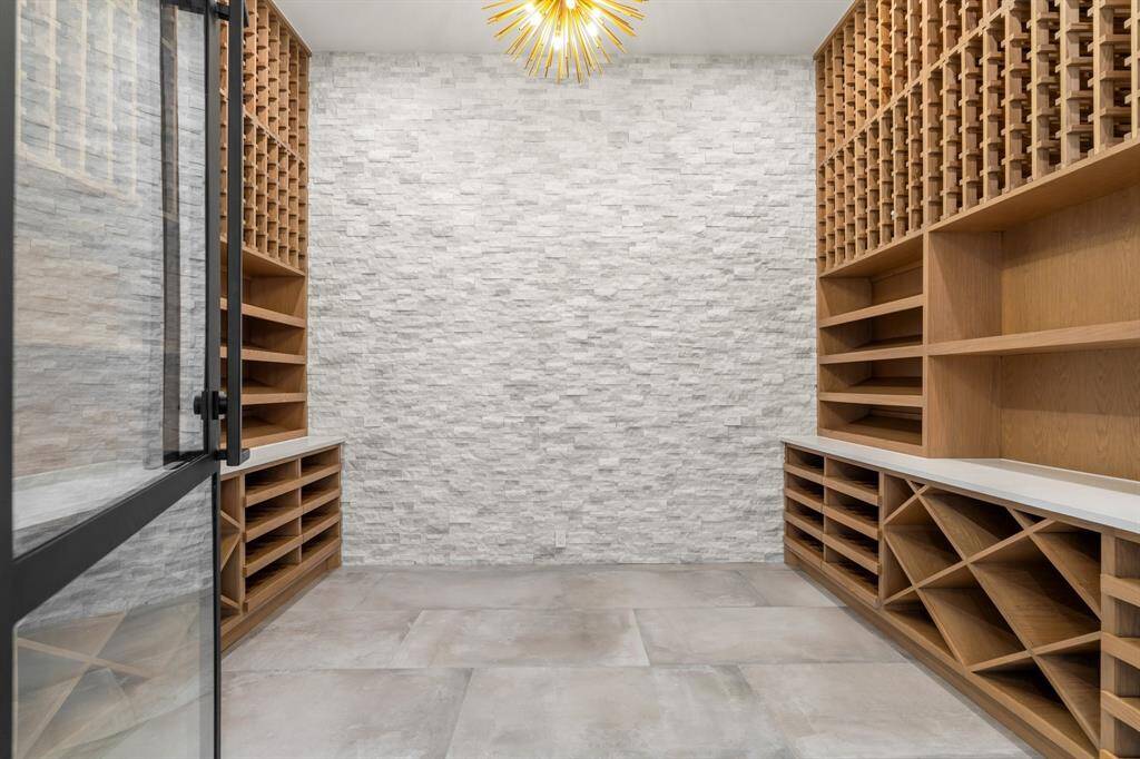 Wine lovers rejoice! This state-of-the-art wine room cares for your prized collection with temperature controls, custom cabinetry, a stacked-stone feature wall and a sea urchin-style light fixture.