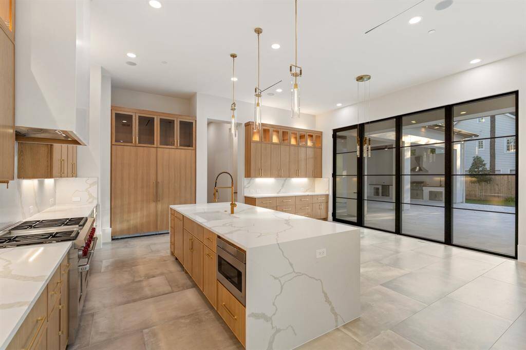 This work-of-art kitchen impresses with generous custom cabinetry, quartz countertops, and a fleet of upscale appliances, including a vented six-burner Wolf range with a griddle, double ovens and a pot filler; a Sub-Zero cabinet-front refrigerator-freezer; dishwasher; and Sharp microwave drawer.