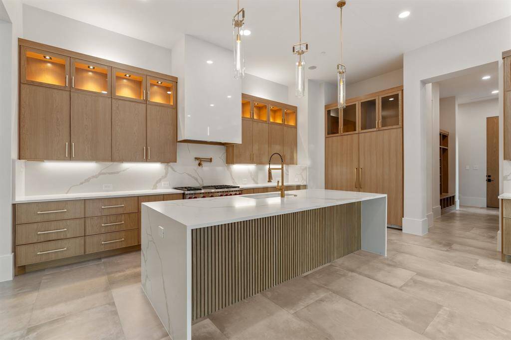 The sunny breakfast area and oversized waterfall center island/breakfast bar provide plenty of space for casual dining. A separate catering kitchen and walk-in storage pantry add exceptional convenience to this dream kitchen.