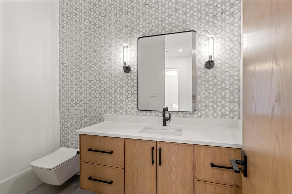Located off the butler’s pantry, this powder room creates a chic design statement with a wall-mounted Toto commode, Carrara marble mosaic tile, a wood vanity and handsome sconces.