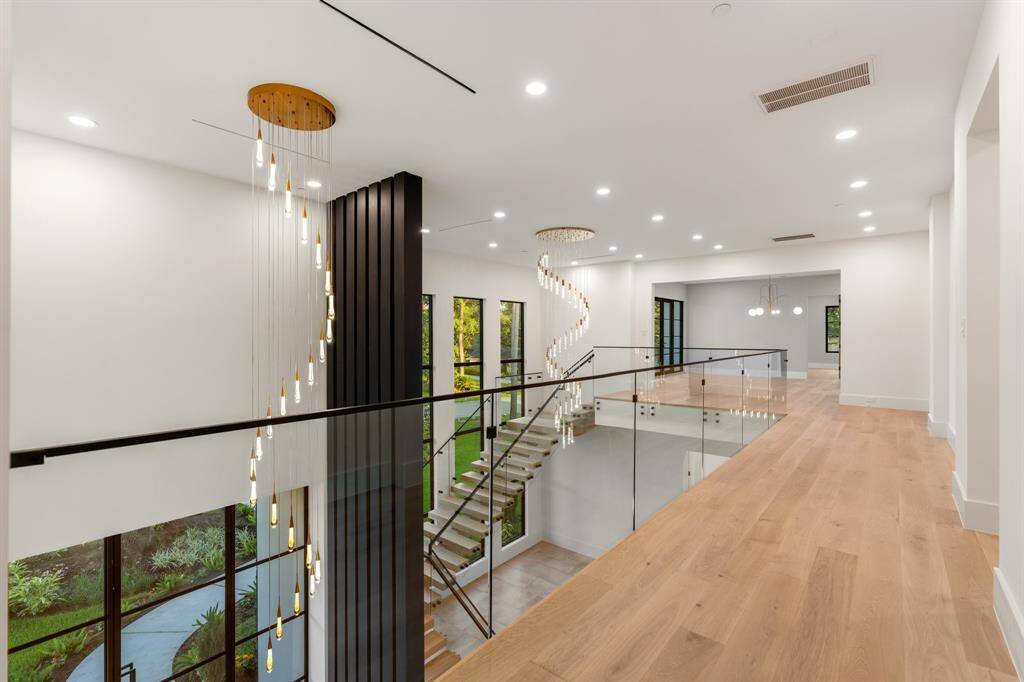 Cascading chandeliers and two-story-tall wood accents draw the eye skyward, while the mezzanine enjoys views into the foyer and formal dining room.