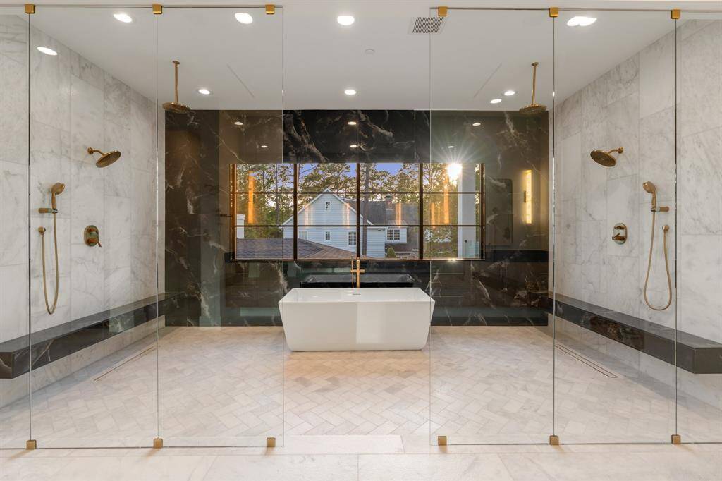 Indulge in the massive wet room, where two separate shower areas with benches, multiple rain showerheads and handheld sprayers flank a freestanding soaking tub.