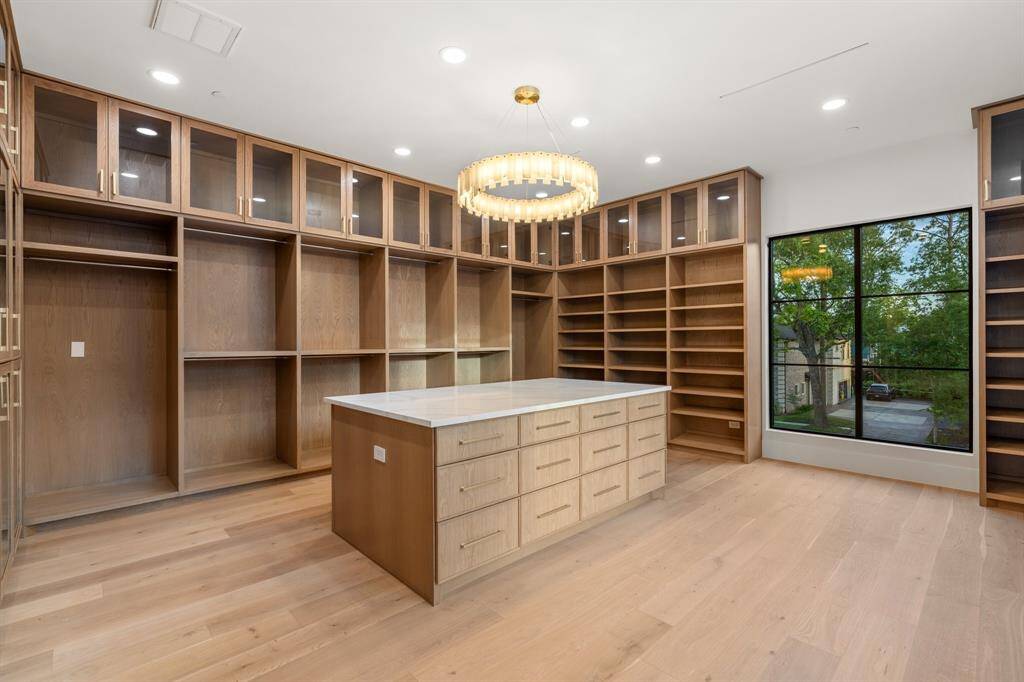Throughout this fashion lover’s dream closet, you’ll find ample shoe shelving, double hanging rods, glass cupboards for bags and boots, plus a convenient packing island surrounded by drawers.