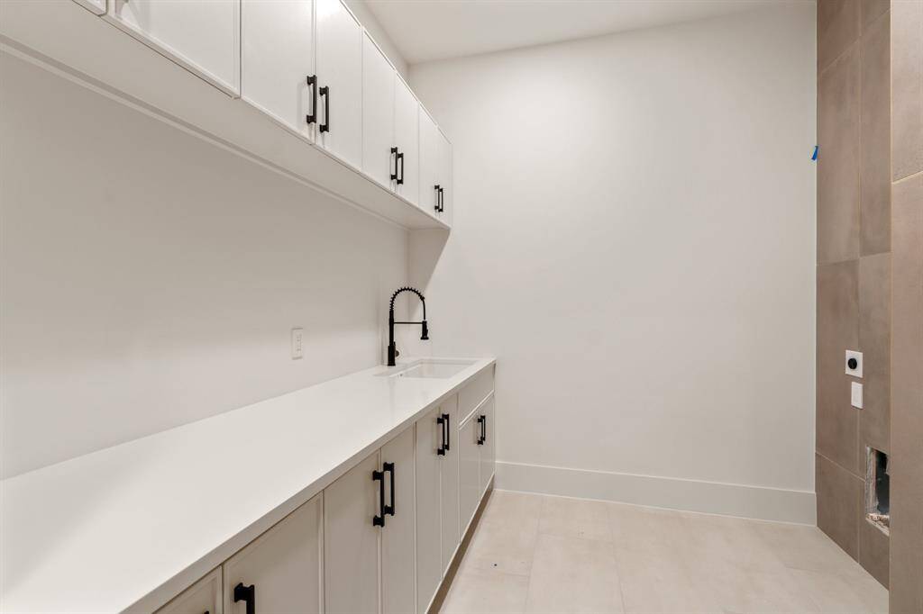 Placed just outside the primary suite vestibule, this laundry room provides ample folding and storage space, plus connections for a full-sized stackable washer and dryer.