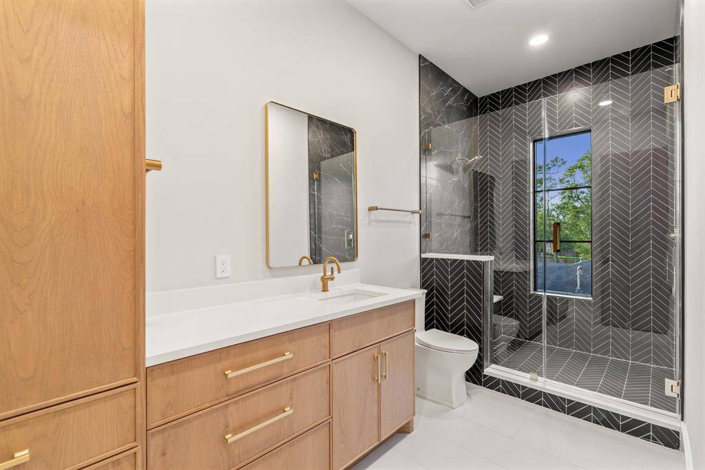 Chevron tile makes a bold design statement in this attached bathroom equipped with generous storage and a walk-in rain shower.