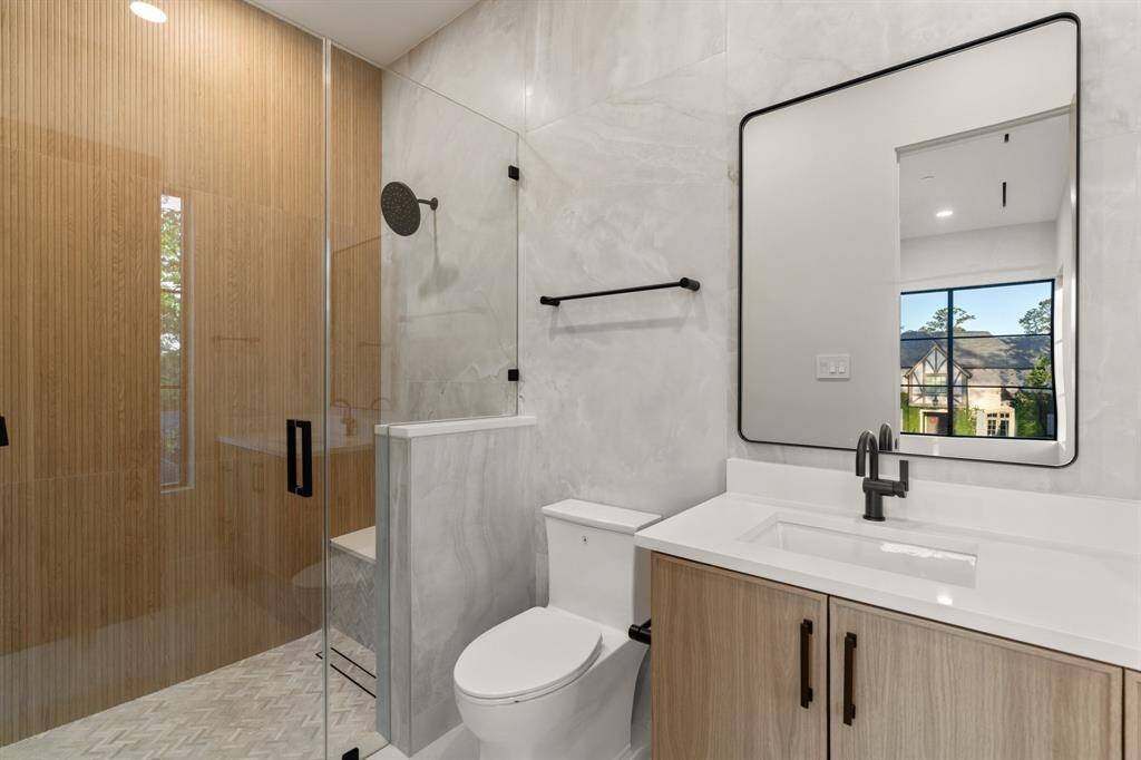 In this ensuite secondary bathroom, you’ll find luxurious floor-to-ceiling tile, a walk-in rain shower and a roomy vanity.