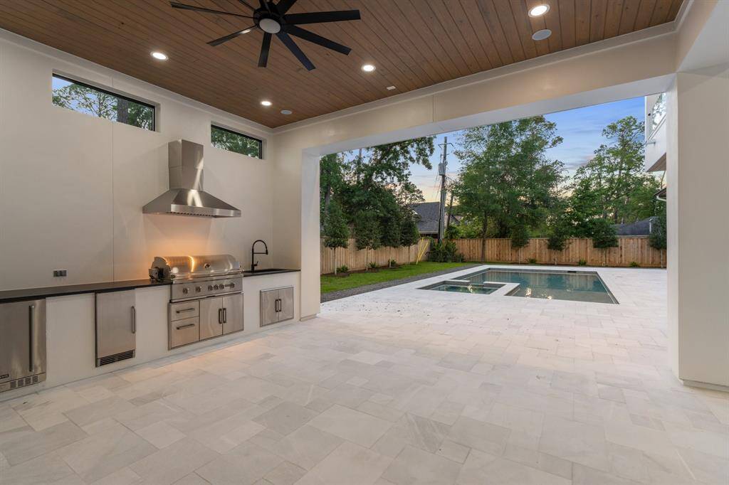 Grill masters take note! This beautifully equipped summer kitchen comes complete with a 48-inch grill with a blower/vent hood, a built-in refrigerator and storage, all by Coyote. A sink and a long stone countertop add convenience for prepping and serving.