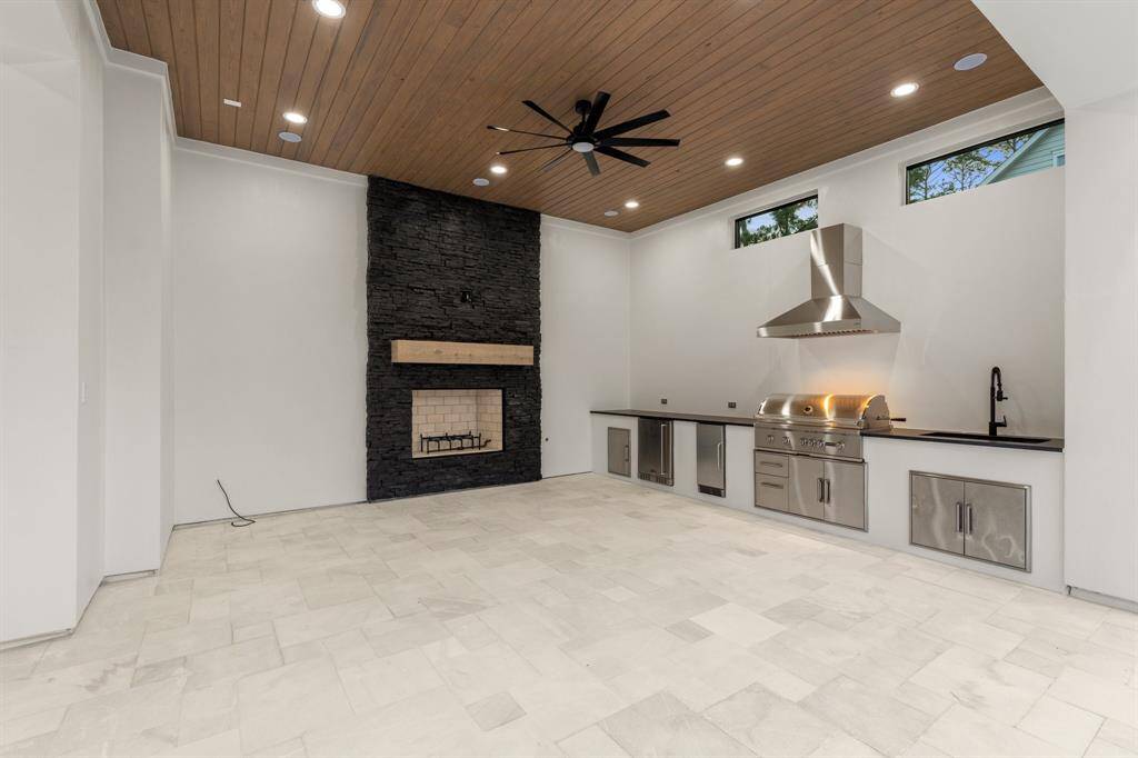 A gas fireplace and an oversized ceiling fan ensure year-round comfort in this outdoor space, perfect for summer barbecues or gameday grilling.