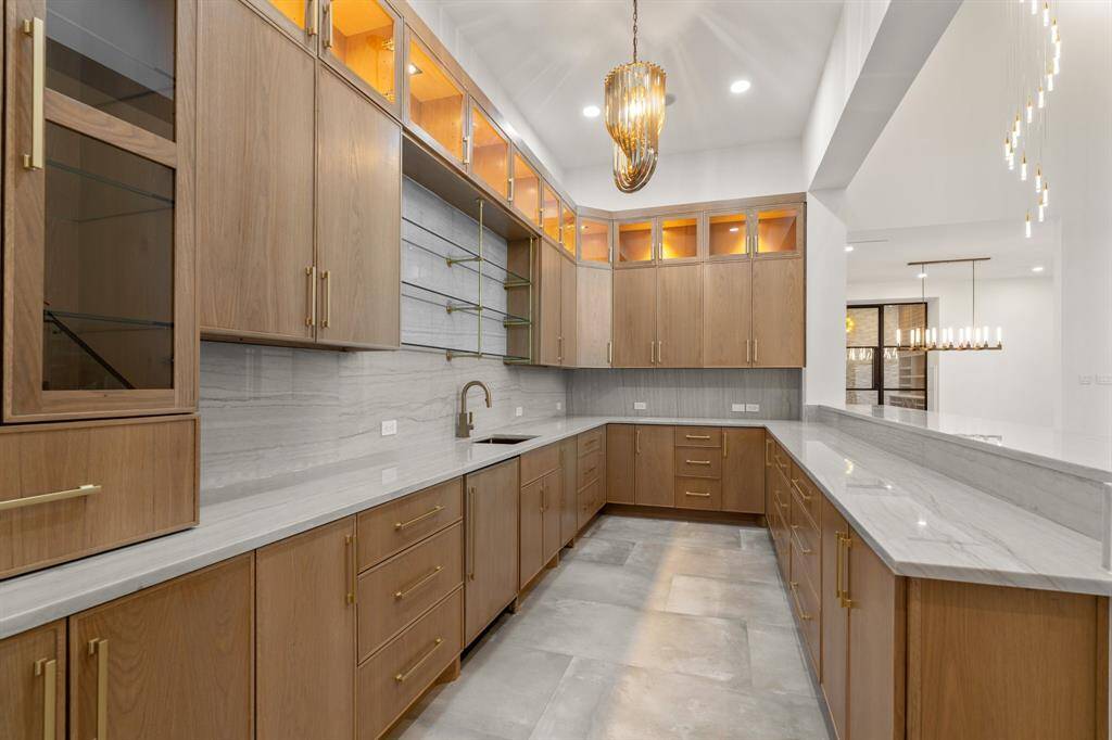 Refreshments are always close at hand thanks to the beautiful wet bar, where custom illuminated cabinetry and natural quartz countertops surround a refrigerator and ice maker.