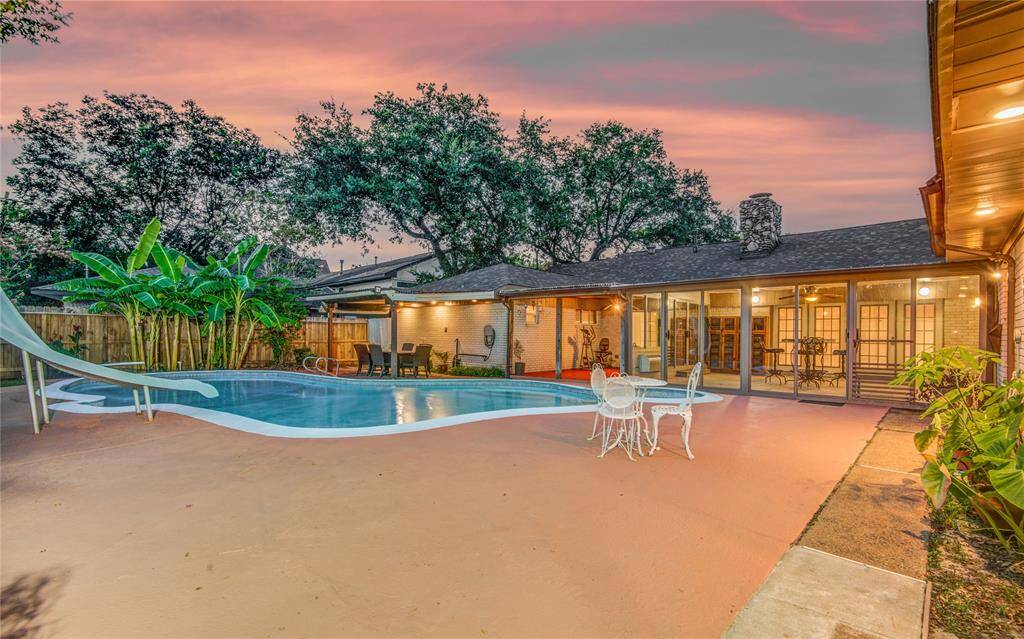 Covered patios spaces & glassed in sun room & glimmering blue pool