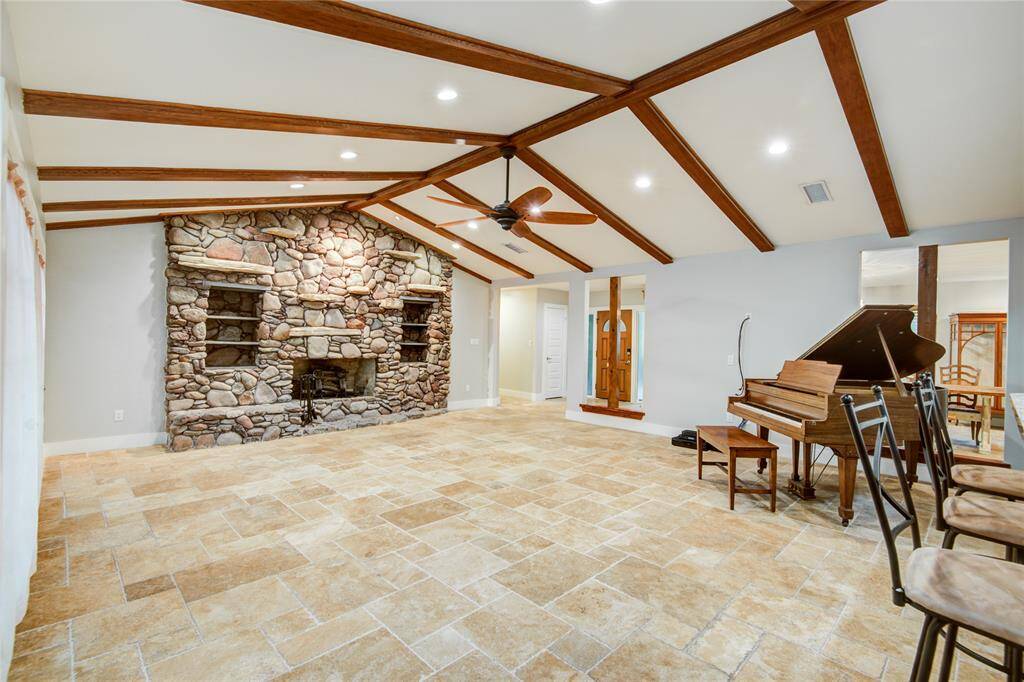 Stone fireplace, travertine floors, wood beams on vaulted ceiling open concept from the breakfast bar off the kitchen