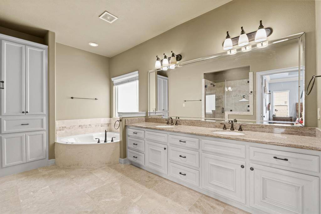 Relax after a long day in this wonderful Primary Bathroom with garden tub, beautiful wood cabinetry, double sinks, and modern fixtures.