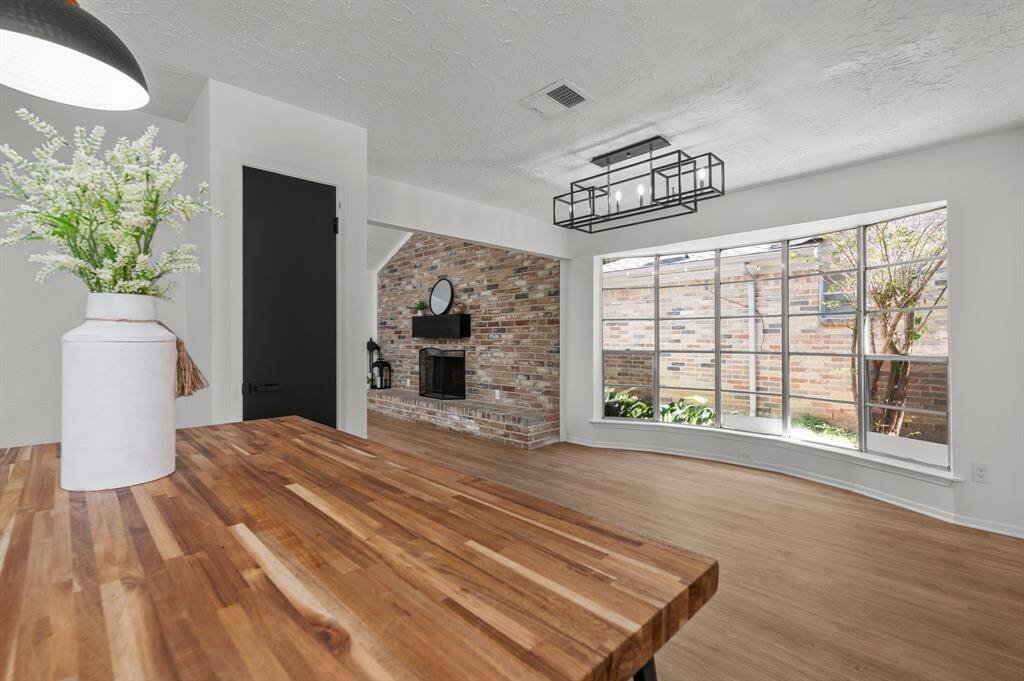 This kitchen features a modern design with white cabinetry, sleek black fixtures, and brand new stainless steel appliances. It includes a spacious sink, a built-in microwave, and a stove. The quartz countertops are complemented by a stylish herringbone backsplash. A wooden butcher block island adds warmth to the space.