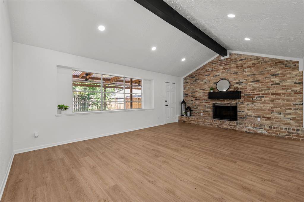 Bright living space with large windows that bring in the nature light throughout the home, wood like flooring, and a cozy brick fireplace. Modern lighting and an open layout enhance the room’s charm. Ideal for relaxation and entertaining.