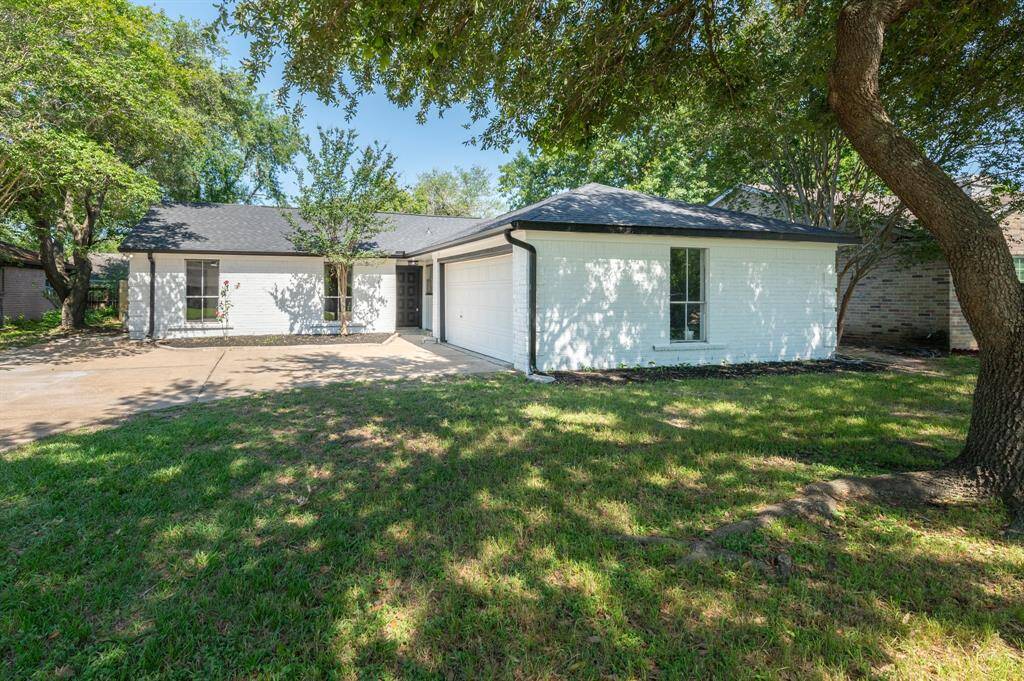 Charming single-story home with a clean white exterior, two-car garage, and a spacious driveway that has plenty of parking space. Surrounded by mature trees and a well-maintained lawn, it offers a welcoming and serene front yard.