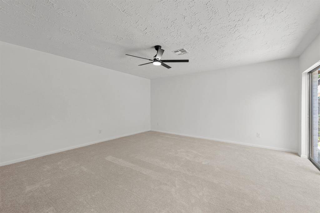 The primary bedroom shows a spacious, empty room with brand new light carpet, and a ceiling fan. A large window or sliding door allows natural light to brighten the space.