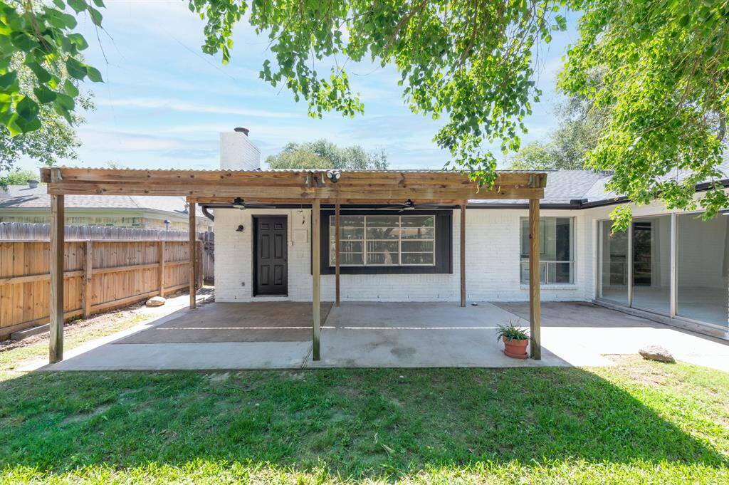 Charming backyard with a spacious covered patio, perfect for outdoor relaxation. The area features a wooden patio, lush green lawn, and privacy fence, offering a serene space for leisure and entertaining.