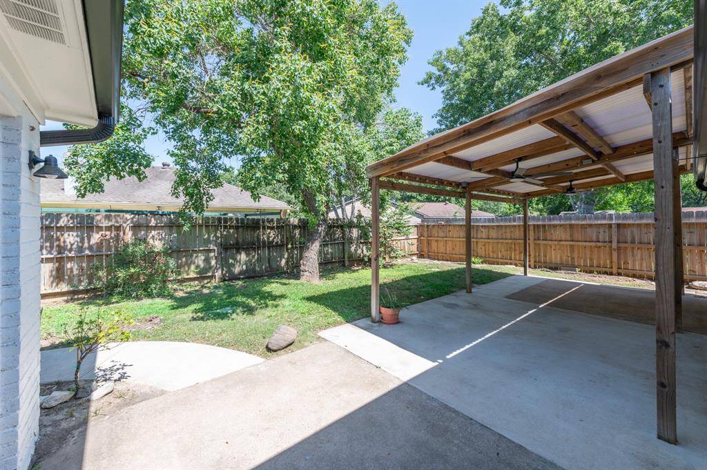 This backyard has a covered patio area featuring a wooden like covered patio, concrete flooring, and a well-maintained lawn. The space is enclosed by a wooden fence, providing privacy and a cozy outdoor setting.