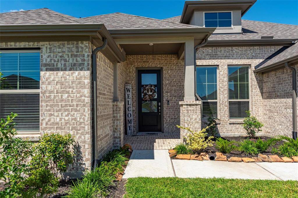 Attractive walkway and front entryway of the home with brick and stucco exterior.