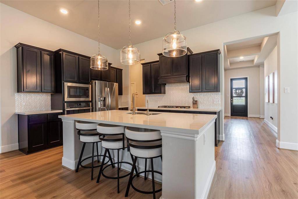 Enhanced kitchen with upgraded built-in appliances. Spacious island kitchen with high ceilings, Omega stone counter tops, bar stool seating and attractive light fixtures.