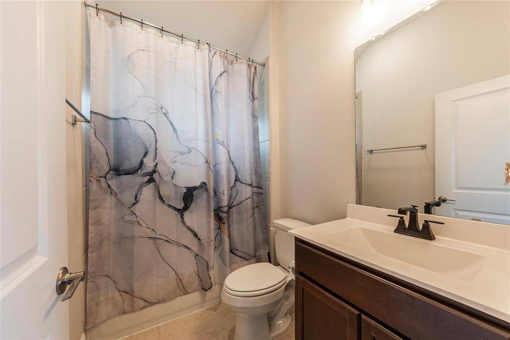 Full sized spare bath with tile flooring and shower/tub combo.