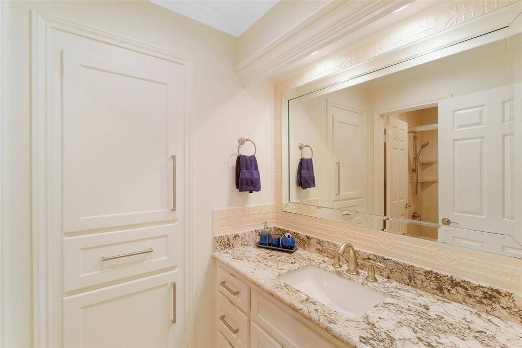 En suite bathroom for guest bedroom with granite countertops and custom cabinets with ample storage. This area is connected to separate water closet with shower.