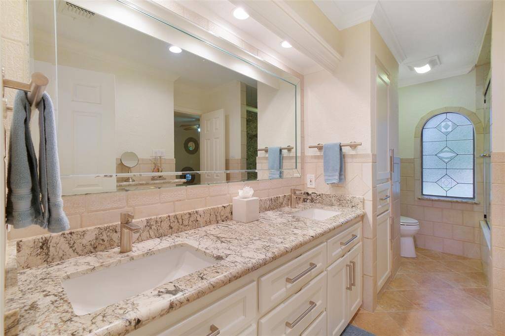 Jack and Jill Bathroom upstairs with double sinks, granite countertops, custom cabinets, ample storage, shower/tub combo.