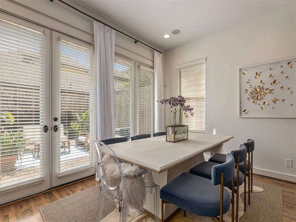 Bright dining area with large windows, elegant decor, and a modern table. The space features comfortable seating and a charming view of the outdoor patio.