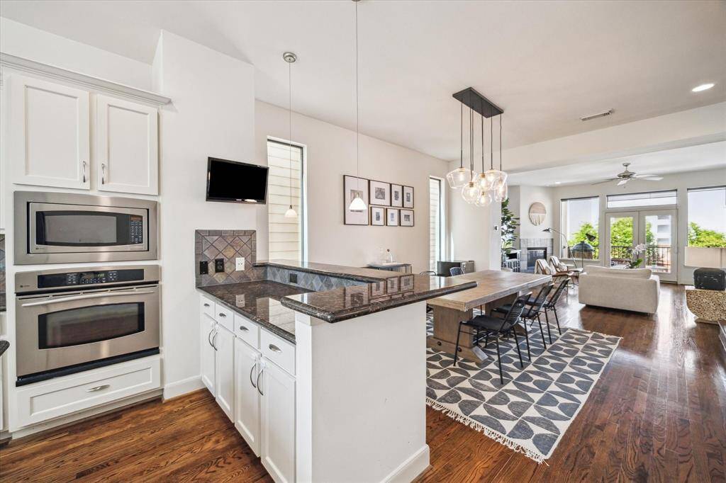 Another view of the kitchen showing the breakfast bar. Equipped with top-of-the-line appliances including a GE stainless steel convection oven, built-in microwave, new Bosch dishwasher (2024),  and a GE gas cooktop with downdraft vent located in the island.