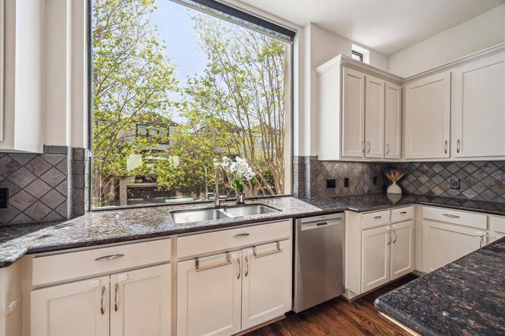 A closer up view of the oversized window above the double basin sink, offering a serene view of the mature trees and creating a treehouse-like atmosphere.