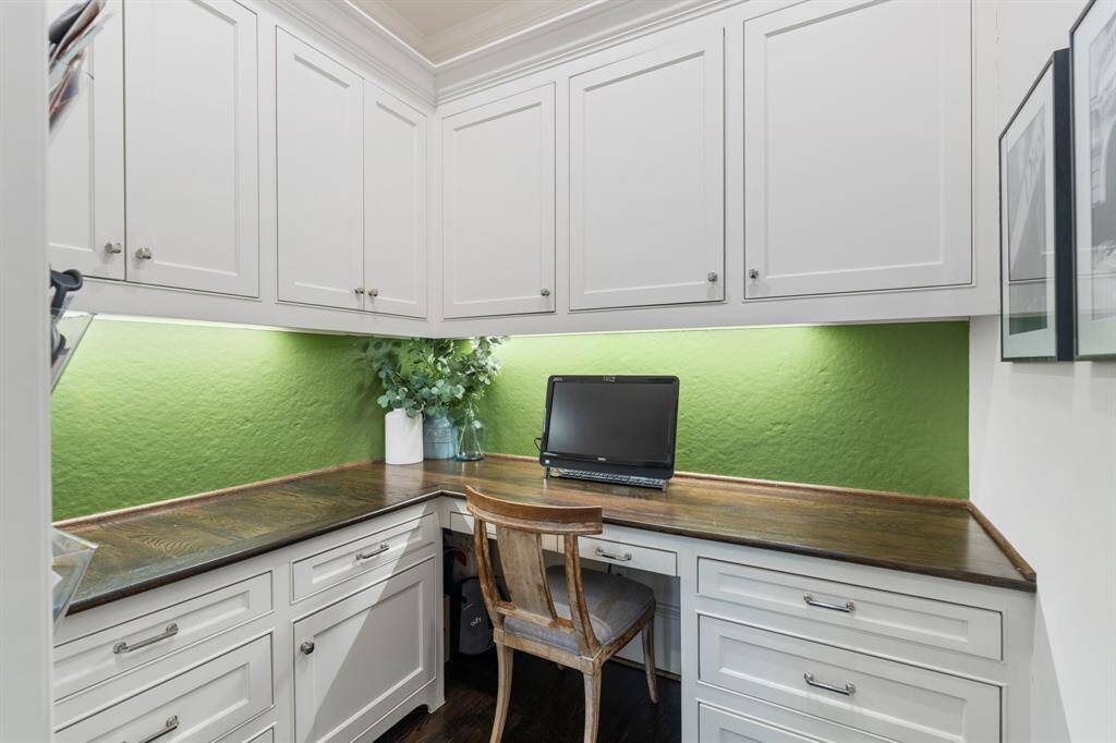 This charming built-in workspace features abundant cabinetry, rich wood countertops, and a vibrant green accent wall that adds a cheerful pop of color to the functional design.