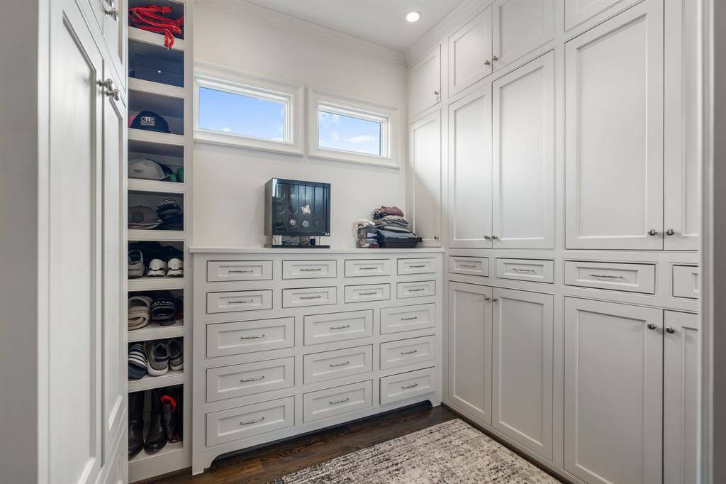 This impeccably designed primary closet features extensive custom cabinetry, a wall of built-in drawers, and dedicated shelving for shoes and accessories.