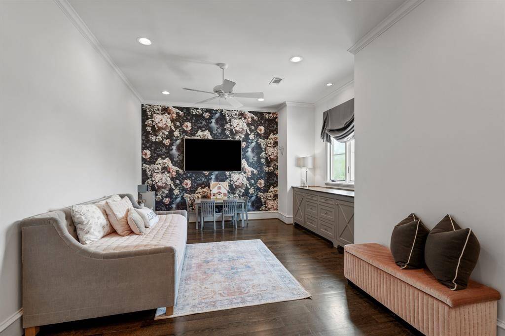 This stylish secondary bedroom blends whimsical charm with functionality, featuring a bold floral accent wall, cozy seating, and a built-in desk area bathed in natural light.