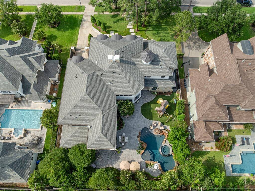 This aerial view reveals the expansive layout of the estate, showcasing a resort-style backyard with a custom pool, spa, play area, and multiple outdoor entertaining zones surrounded by lush landscaping.