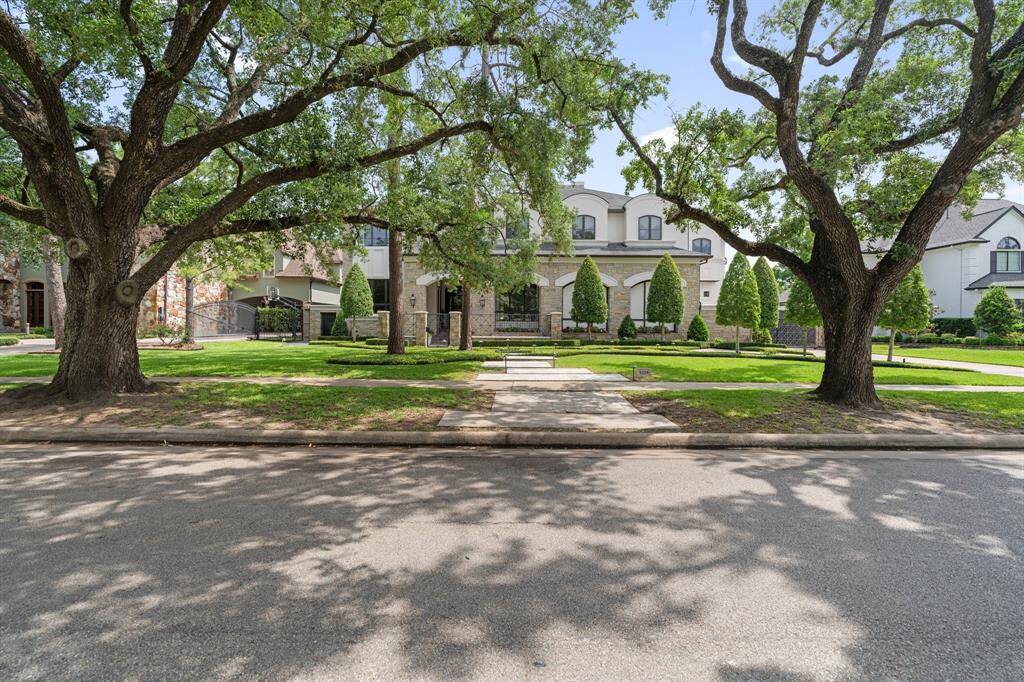 Framed by mature oak trees and meticulous landscaping, this grand estate commands attention with its elegant façade and sweeping front lawn. A wide stone walkway leads to a gated entrance, setting the tone for the refined sophistication found within.