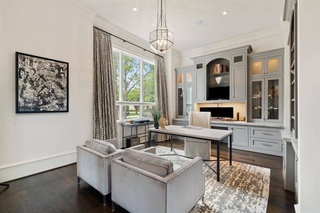 This elegantly appointed home office combines form and function with custom built-in cabinetry, a sophisticated neutral palette, and ample storage integrated seamlessly into the design. A large window floods the space with natural light, creating an inspiring and comfortable environment for productivity and creativity.