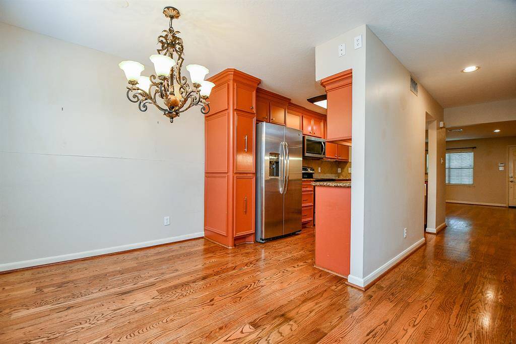Elegant dining area featuring rich hardwood floors, an ornate chandelier, and seamless access to the kitchen for effortless entertaining.