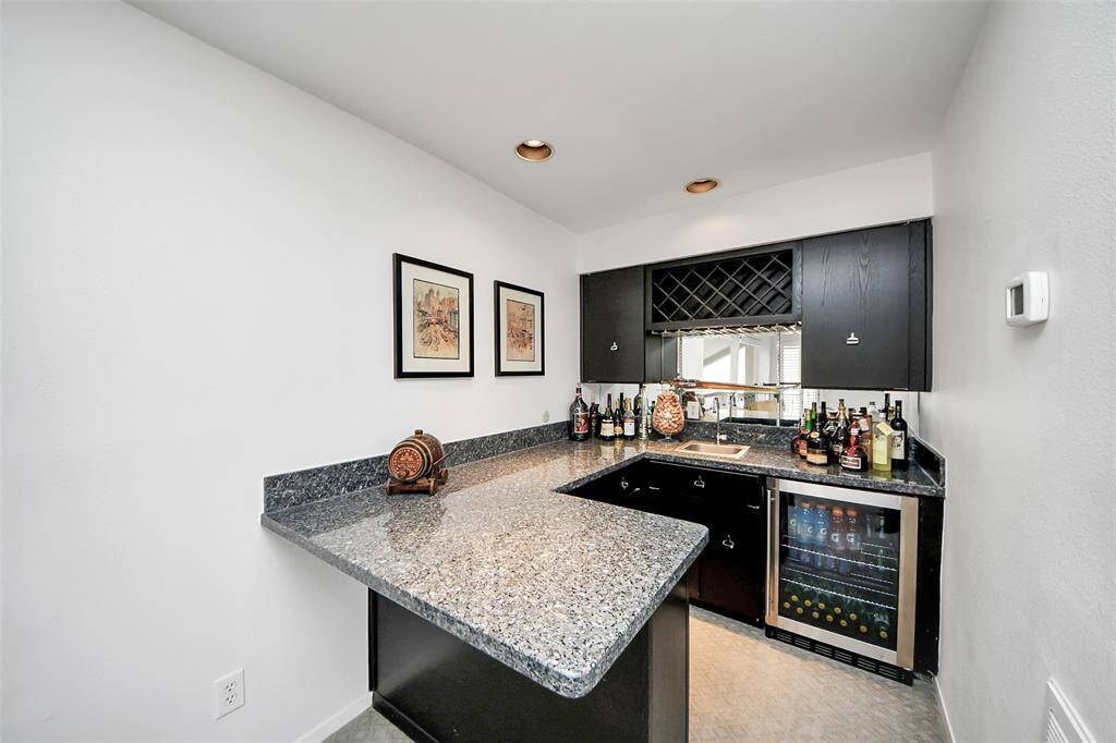 A fully equipped wet bar featuring a beverage fridge, expansive granite countertops, and ample cabinetry for the bartender in you!