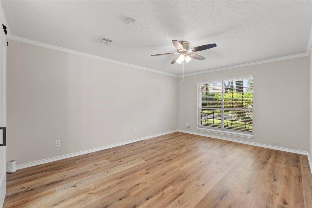 The primary bedroom is on the first floor, just past the entry to the right as you enter. The same gorgeous LVP floors, neutral paint, white accents and crown molding, and a ceiling fan!