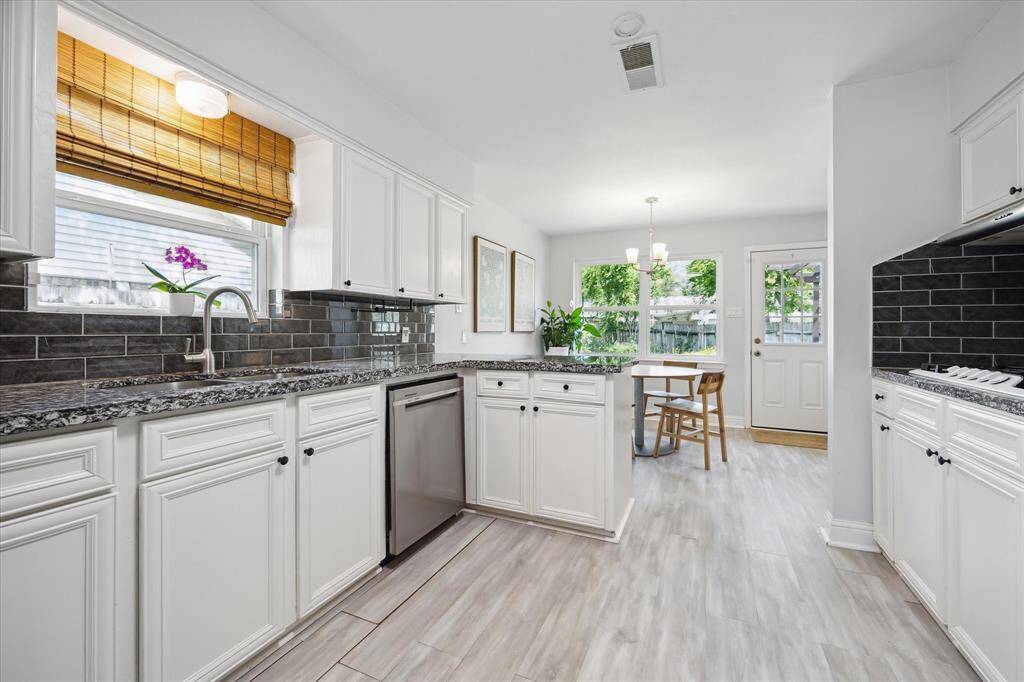 The light bright kitchen has granite slab countertop and coordinated gray subway tile backsplash..