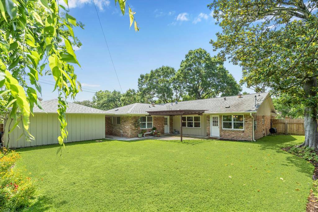 From the northwest corner of the beautiful spacious backyard looking toward the house, sideyard and a large magnolia tree.