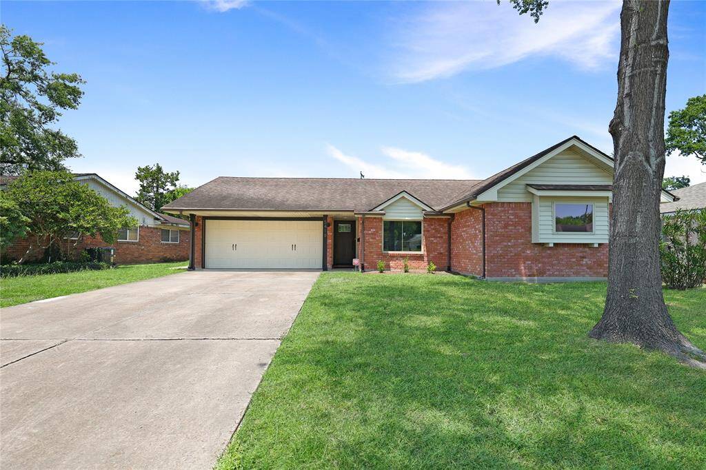 Charming single-story brick home with two-car garage. It features a spacious front yard with mature trees and a well-maintained lawn, offering excellent curb appeal.