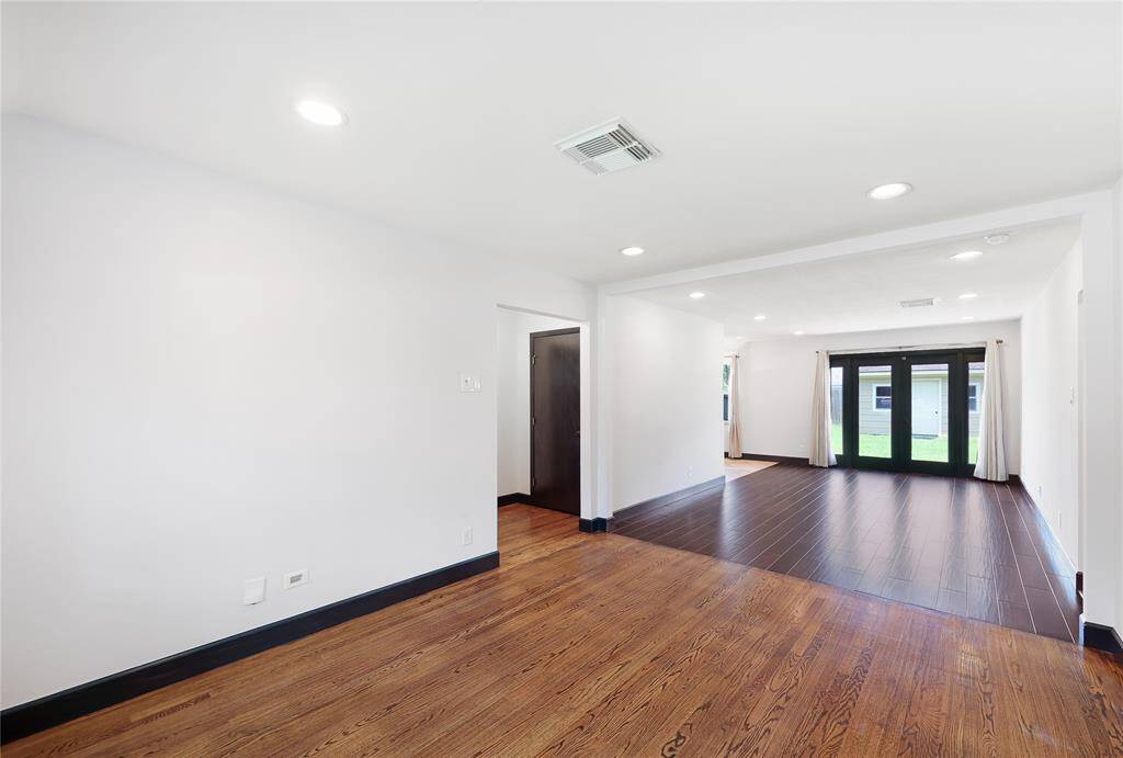 Bright, open living area with hardwood floors and recessed lighting, large windows allowing plenty of natural light