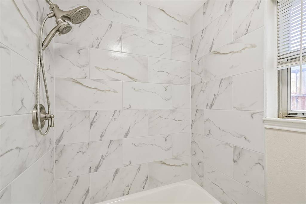 Primary bath has shower surround with modern tile surround