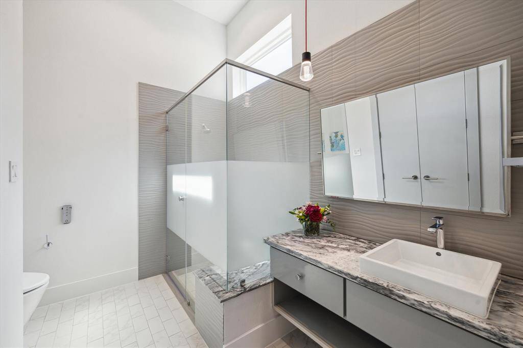 The spacious en-suite bathroom features a glass-enclosed walk-in shower and modern finishes.