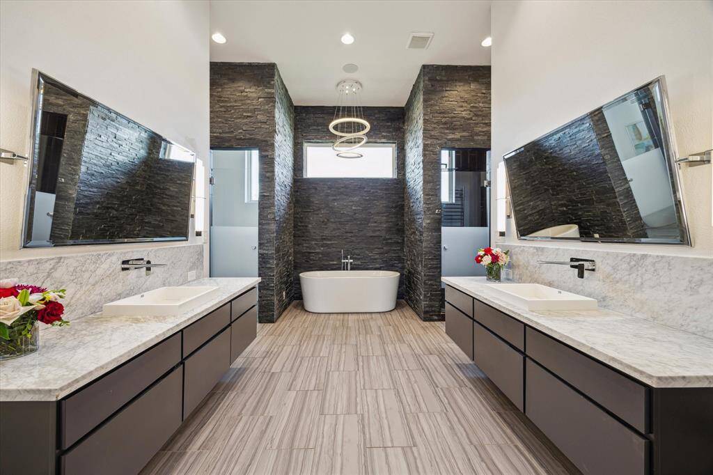 This spa-inspired primary bathroom offers dual vanities, freestanding soaking tub, and a large walk-in shower.