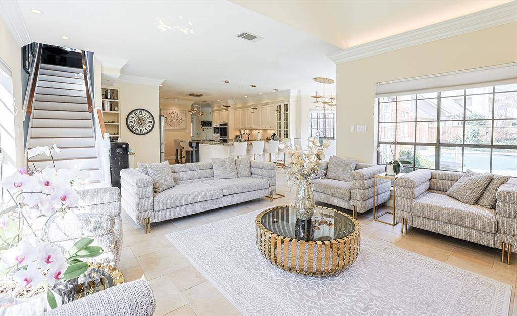 A beautifully designed living space with soaring ceilings, a modern fireplace, and built-in shelving. Expansive windows flood the room with natural light, while the elegant furnishings create a comfortable yet refined atmosphere.