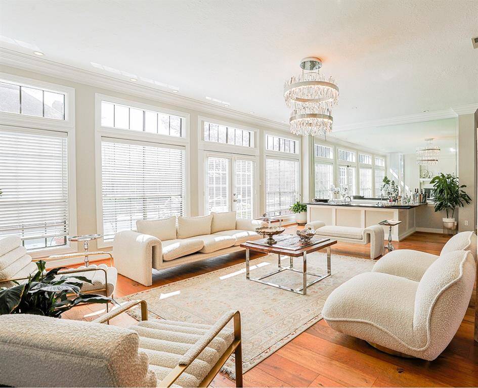 A stylish and inviting formal living space with a mirrored wet bar, crystal chandeliers, and luxurious seating. The open-concept layout and large windows create a bright and elegant ambiance.