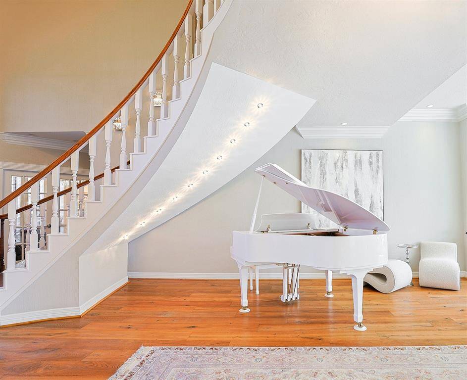 A breathtaking curved staircase with wooden handrails and white balusters serves as a stunning centerpiece in the home’s grand foyer. The soaring ceilings and open layout add to the sense of grandeur, while natural light highlights the beauty of the hardwood floors.